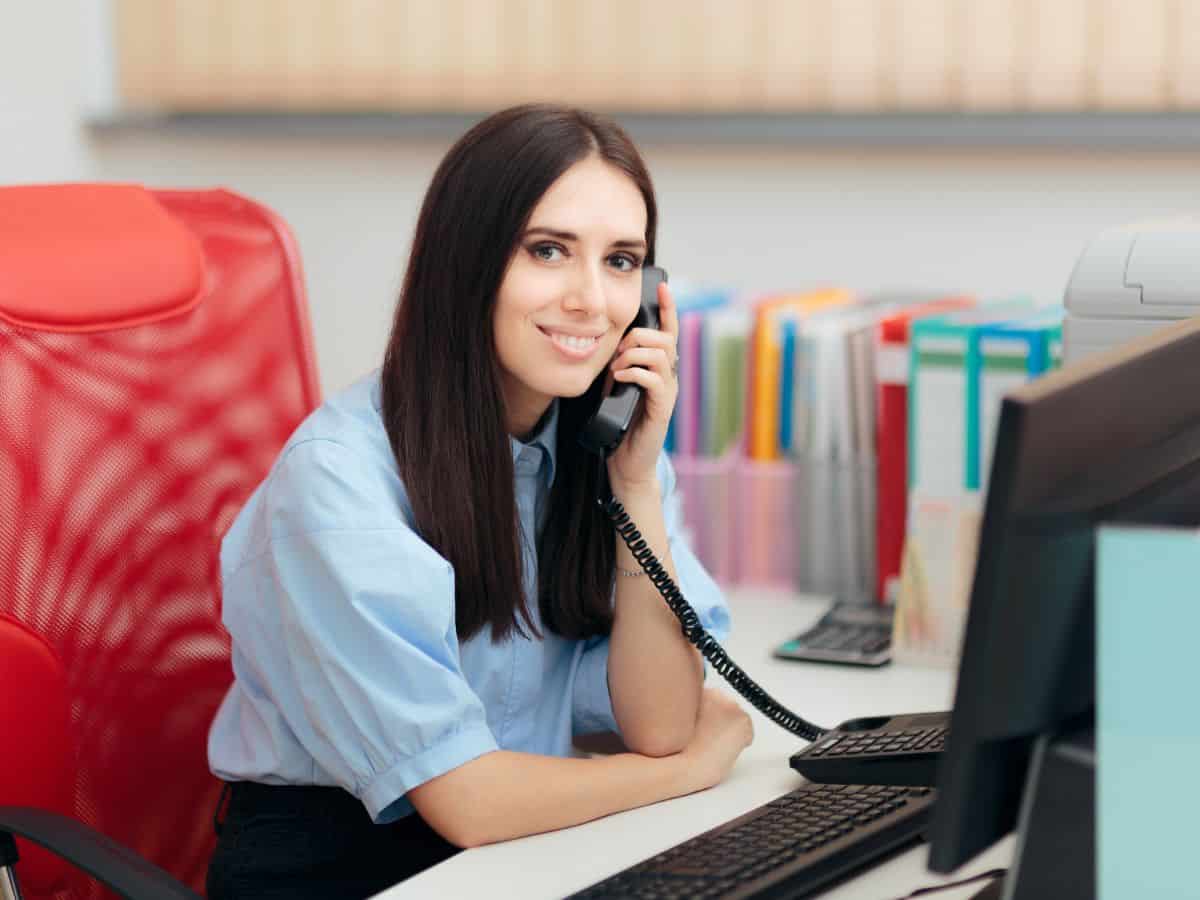 A woman sitting at a desk holding a phone to her ear