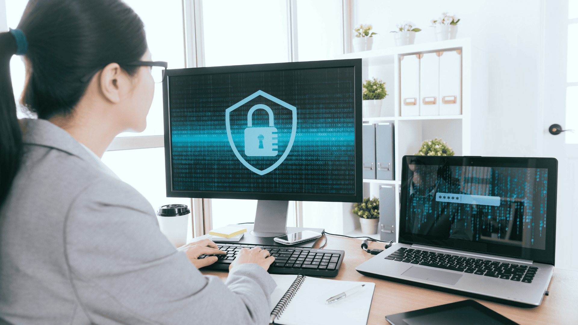 person sitting at a desk looking at multiple computer screens