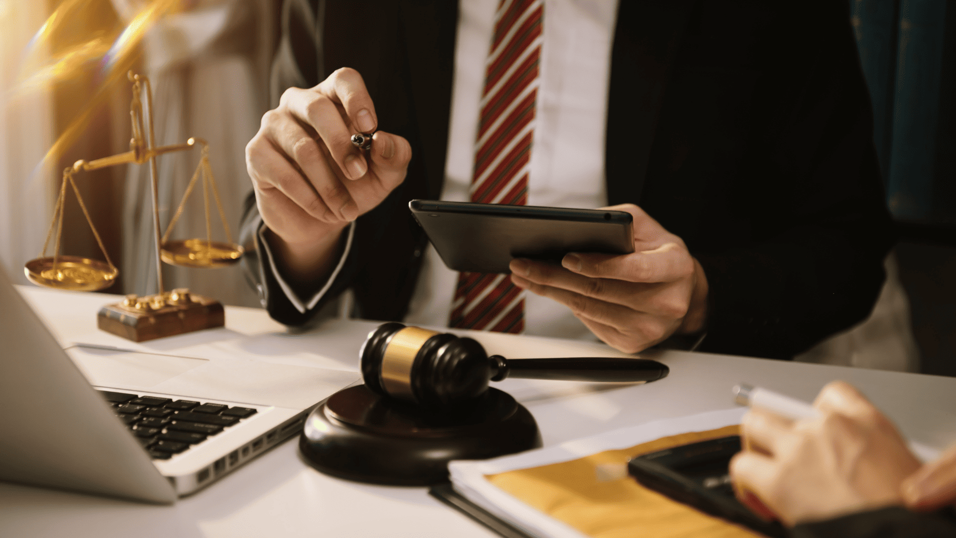 A lawyer sitting behind a desk holding a tablet computer